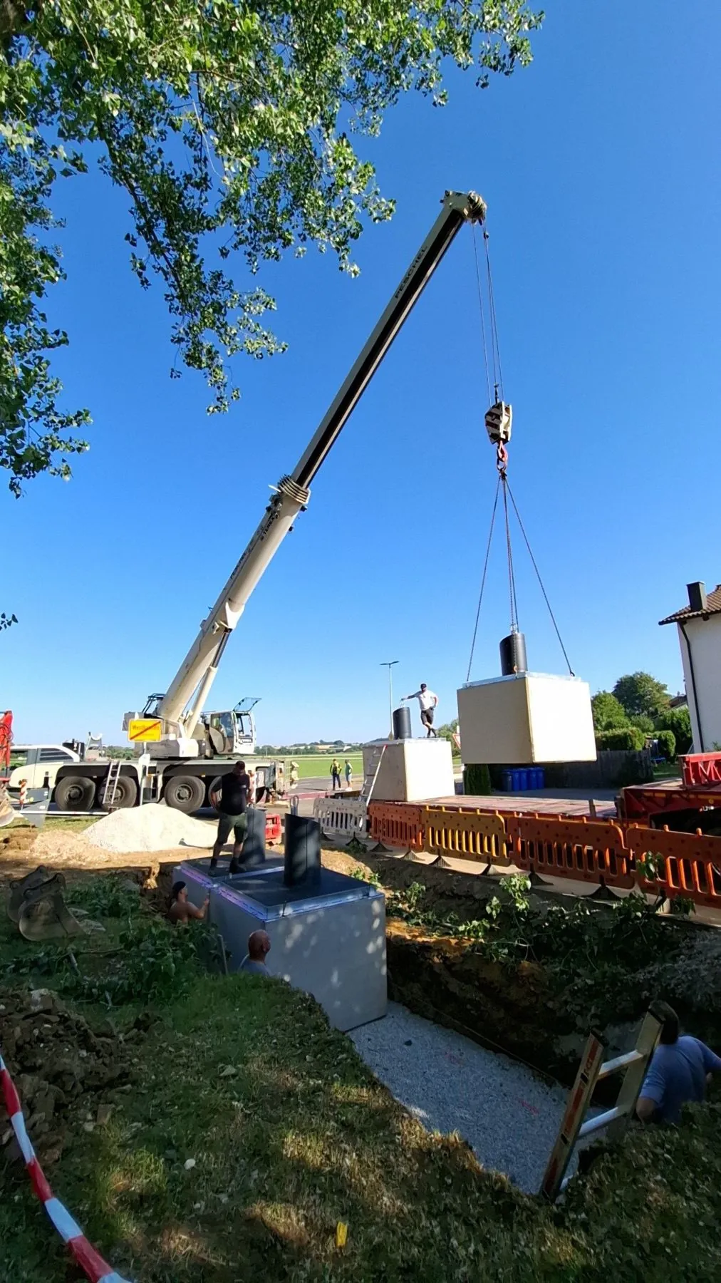 Autokran hebt ein Betonbauwerk in die Baugrube