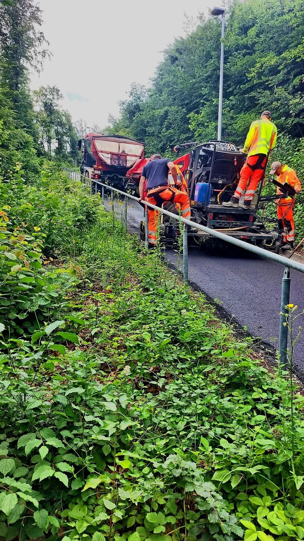 Kolonne baut mit dem Fertiger Asphalt auf dem Weg ein