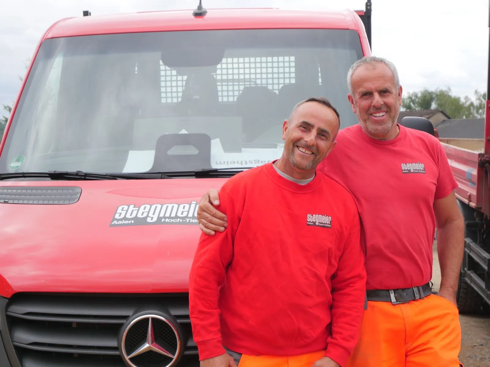 Zwei Brüder in Stegmeier-Kleidung vor einem roten Transporter