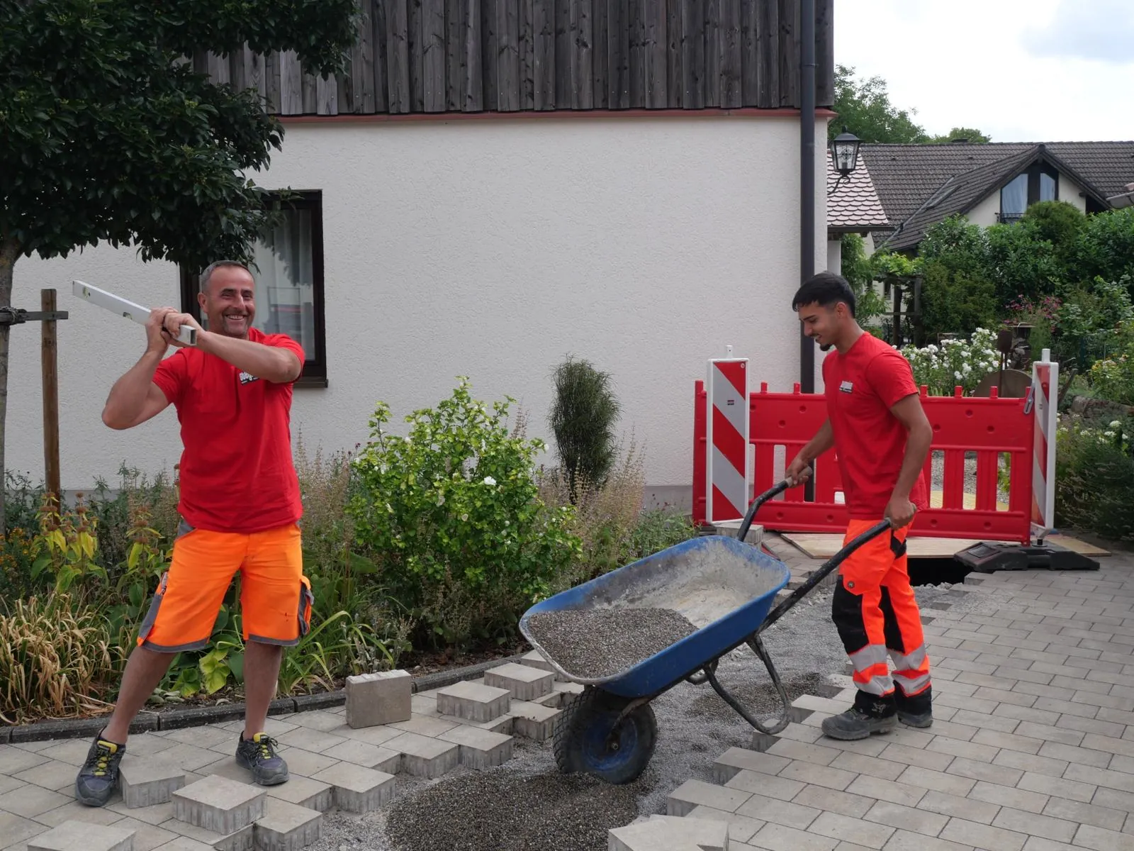 Kollegen beim Pflastern mit Schubkarre