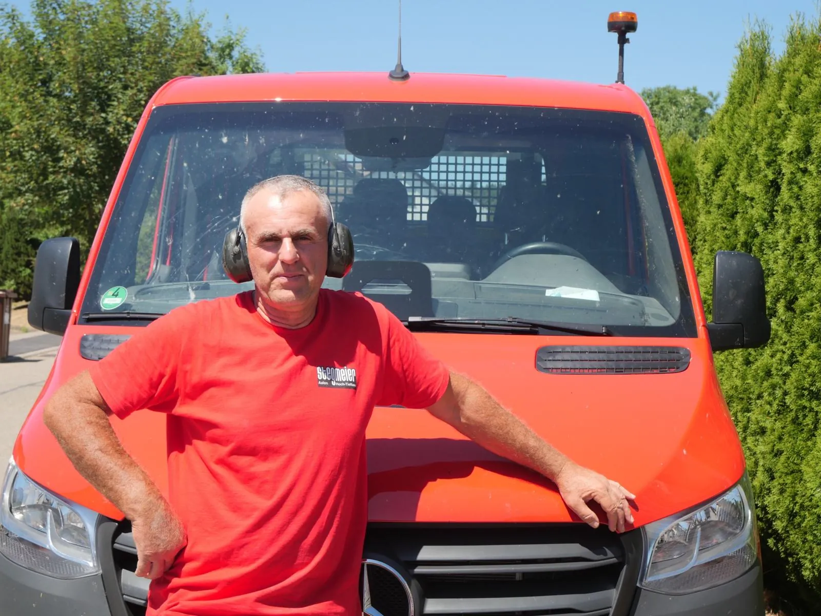 Der große Bruder mit Gehörschutz vor dem roten Stegmeier-Transporter